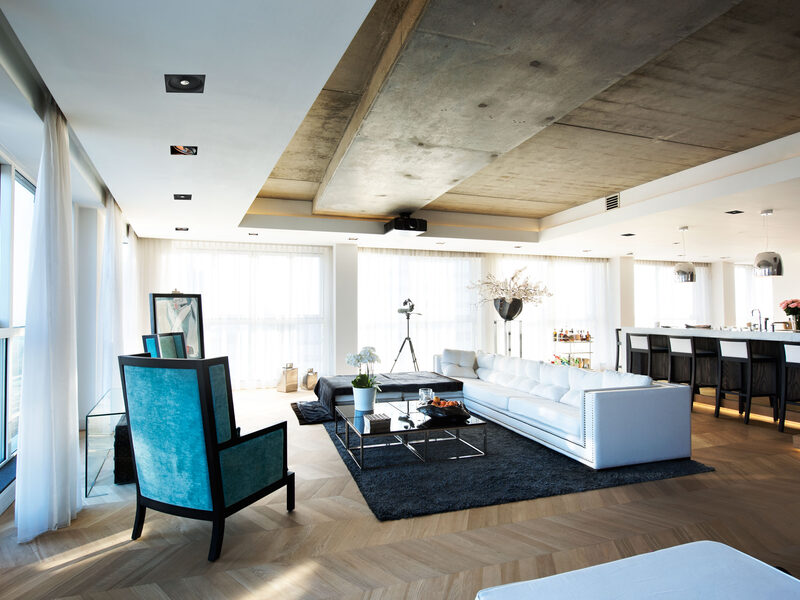 An open-plan penthouse with speakers finished flush into a concrete ceiling.